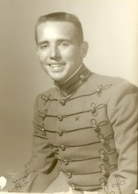 Studio portrait of a young Graham Nicholson in grey military-academy full dress, braided frogging and ball buttons, a star at the breast.
