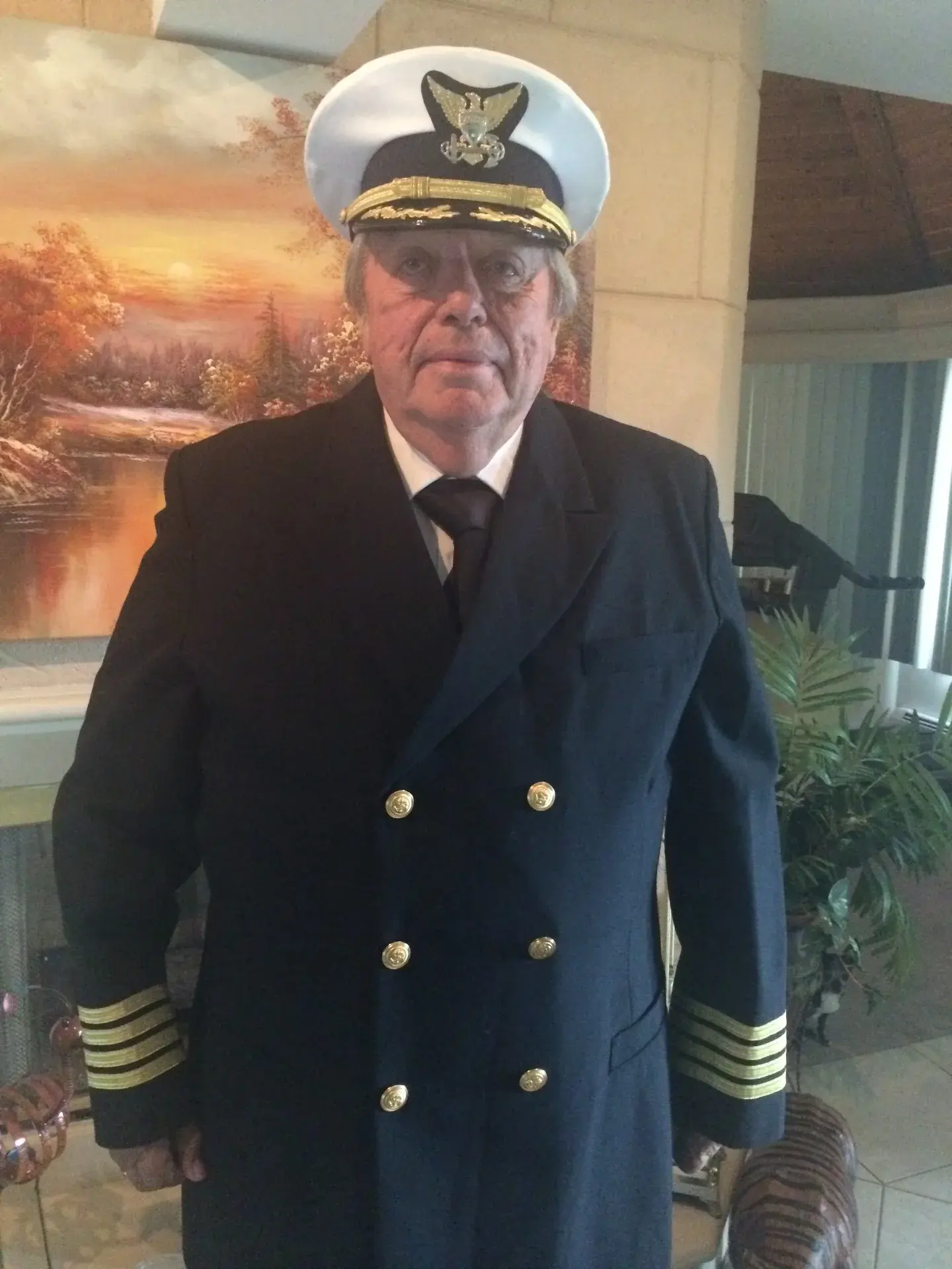 Graham Nicholson in full captain's dress blues: double-breasted jacket with four gold stripes at each cuff and a white peaked cap with eagle and fouled anchor.
