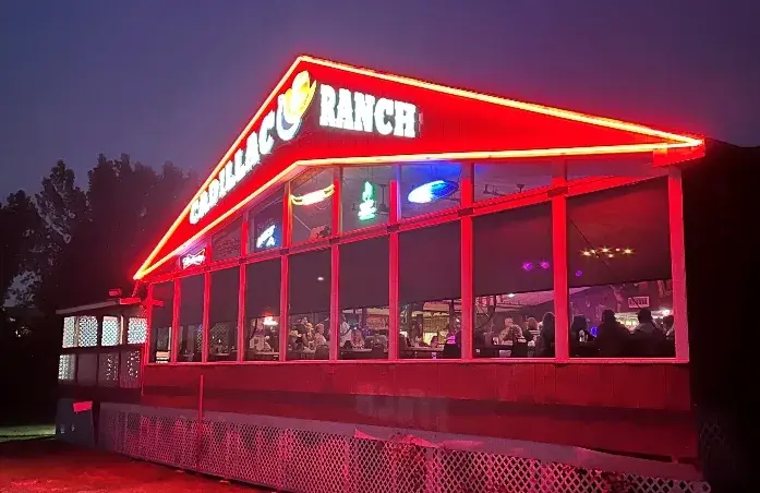 The Cadillac Ranch Restaurant at night, its name in red neon along the roofline.