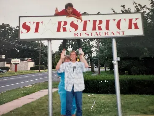 The STARSTRUCK RESTAURANT roadside sign, with two people standing beneath it.