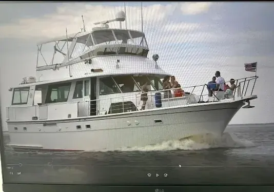 A white flybridge motor yacht underway with passengers aboard.