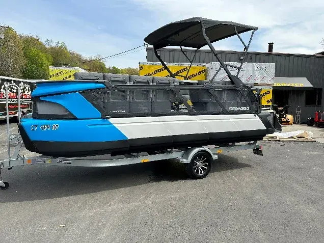 A blue and white Sea-Doo Switch pontoon boat on a trailer.