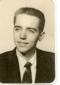 A black-and-white portrait of a young man in a jacket and tie, late 1950s.